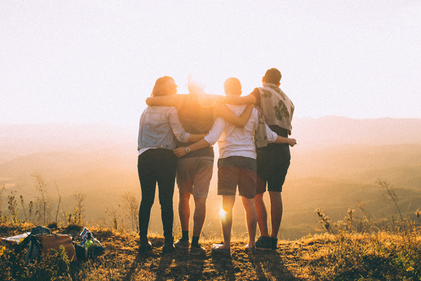 Group of friends hugging on the top of a mountain.